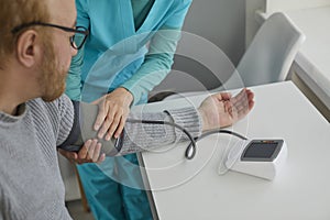 Nurse measure blood pressure of a sick senior mature male patient in clinic closeup.