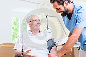 Nurse measuring blood pressure of senior patient