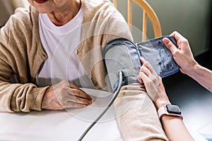 Nurse measuring blood pressure by using automatic blood pressure monitor on senior Asian woman with many medicine bottles of the