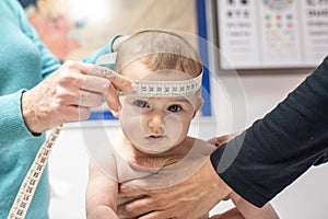 Nurse measuring the cranial perimeter of a baby in a clinic with a tape measure