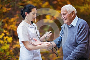 Nurse measuring old patient`s blood pressure