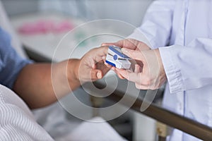 Nurse measuring oxygen saturation of senior female patient in hospital