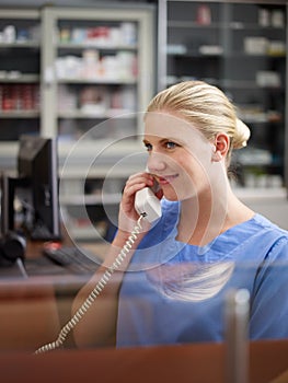 Nurse in medical clinic, speaking on telephone