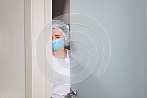 A nurse in a medical mask looked in and winked . Personal medical protection equipment during an epidemic.