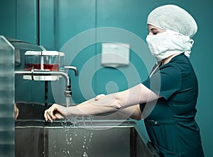 Nurse in medical mask washes hands