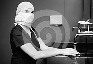 Nurse in medical mask washes hands