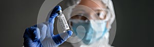 Nurse in medical PPE suit holds bottle with vaccine for COVID-19 cure photo