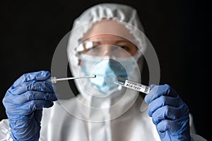 Nurse in medical PPE suit holds tube of coronavirus PCR test