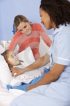 Nurse and mother at girl's bedside in hospital