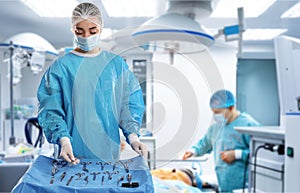 Nurse near table with different surgical instruments in operating room