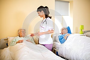 Nurse at nursing home brings medicine to senior immobile woman