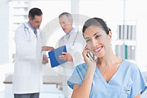 Nurse phoning while her colleagues working photo