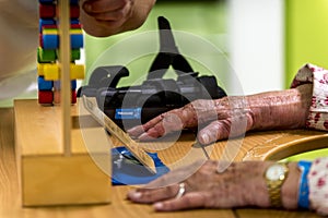 Nurse and physiotherapists helping elderly person to regain her body mobility, with toys