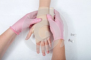 Nurse with pink gloves wrapping young girls hand with ace bandage