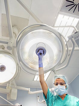 Nurse places surgical lamp on the operating table