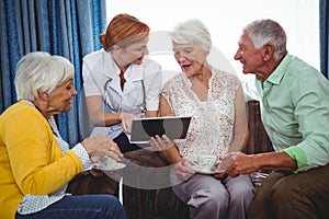 Nurse pointing and showing the screen of a digital tablet to retired person