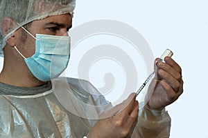 A nurse prepares a dose of vaccine to inject dressed in personal protective equipment PPE