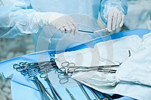 A nurse prepares medical instruments for surgery for surgeons