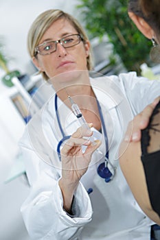 Nurse preparing injection for woman`s arm photo