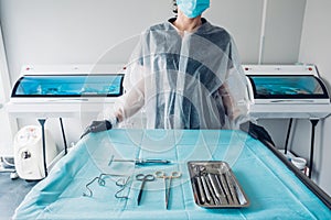 Nurse preparing table with set of sterile surgical instruments for a dental surgery