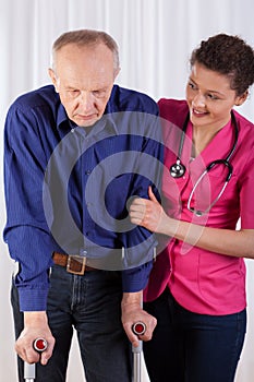 Nurse protecting man on crutches photo