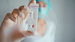 Nurse in protective face mask and gloves holding rapid test for viral disease COVID-19