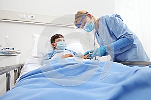 Nurse with pulse oximeter on patient child in hospital bed, wearing protective visor mask, corona virus covid 19 protection photo