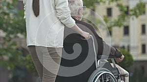 Nurse pushing man in wheelchair, living conditions for disabled people in city