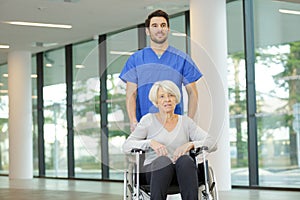 nurse pushing senior patient in wheelchair along corridor