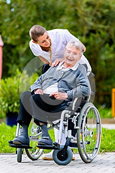 Nurse pushing senior woman in wheelchair on walk