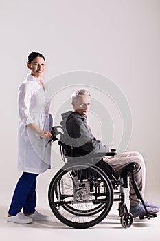 Nurse pushing wheelchair with man in it.