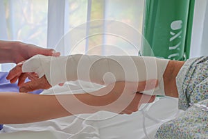 Nurse put on elastic bandage for broken arm of senior patient