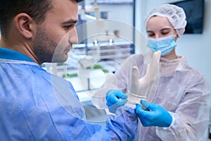 Nurse puts on the doctor disposable sterile gloves