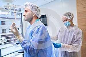 Nurse puts on the doctor a disposable sterile gown