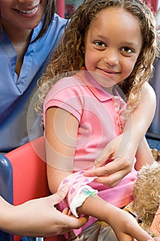 Nurse putting bandage on girls arm