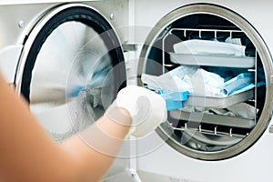 Nurse putting instruments in special craft paper bags into autoclave for processing. Modern laboratory equipment. Tools