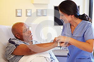 Nurse Putting Wristband On Senior Male Patient In Hospital