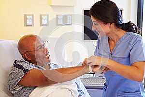 Nurse Putting Wristband On Senior Male Patient In Hospital photo