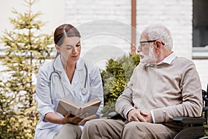 Nurse reading book for disabled man