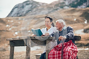 Nurse reading book to senior man outdoor