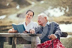 Nurse reading book to senior man outdoor