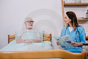 Nurse reading newspaper to senior