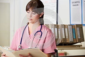 Nurse Reading Patient Notes At Nurses Station