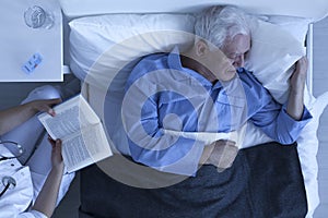 Nurse reading for senior patient