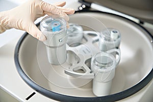 Nurse removing vacuum tube with blood sample from centrifuge, plasma separation