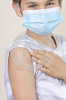 Nurse in rubber protective gloves putting bandage plaster on teenage boy arm after vaccination. Injection covid vaccine