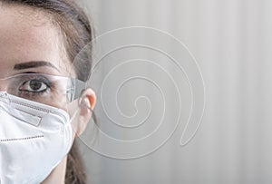 Nurse's close-up half face protrait with protective glasses and N95 mask