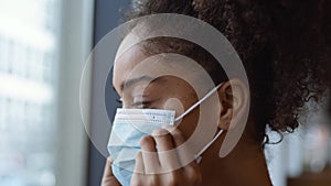 Nurse In Scrubs With Face Mask Looking Out Of Window In Busy Hospital During Health Pandemic