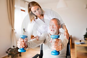 Nurse and senior man in wheelchair during home visit.