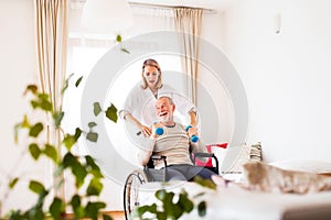 Nurse and senior man in wheelchair during home visit.